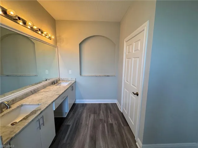 Full bath featuring wood finished floors, baseboards, a textured ceiling, and double vanity
