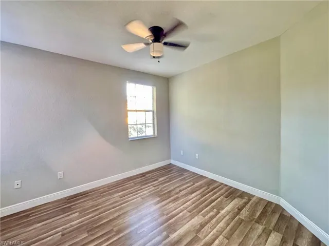 Unfurnished room with wood finished floors, baseboards, and ceiling fan