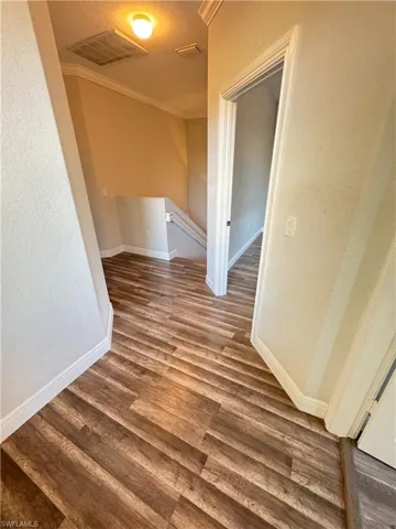 Hallway featuring an upstairs landing, wood finished floors, crown molding, and baseboards