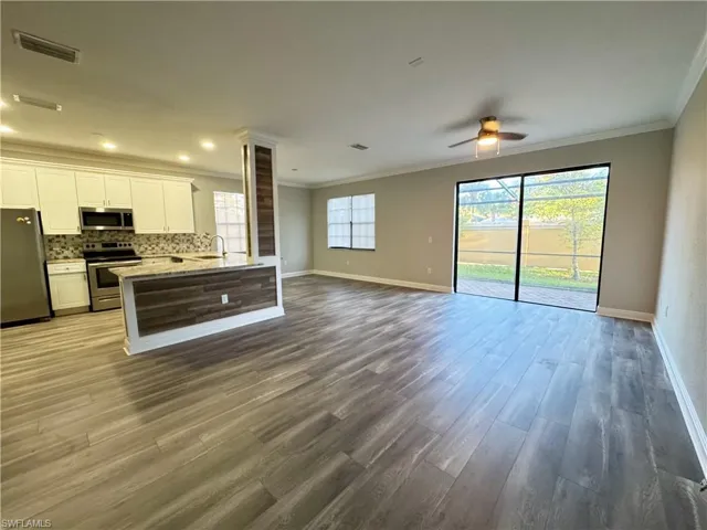 Kitchen with stainless steel appliances, open floor plan, a ceiling fan, ornamental molding, and a sink