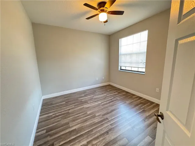 Spare room with dark wood-style flooring, baseboards, and a ceiling fan