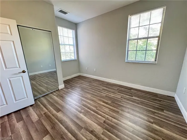 Unfurnished bedroom with dark wood-style flooring, baseboards, and a closet