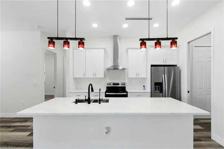 Kitchen with white cabinetry, decorative light fixtures, stainless steel appliances, open floor plan, and recessed lighting