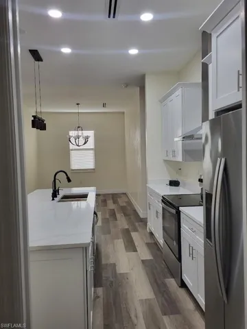 Kitchen featuring stainless steel fridge with ice dispenser, electric stove, dark wood-type flooring, pendant lighting, and recessed lighting