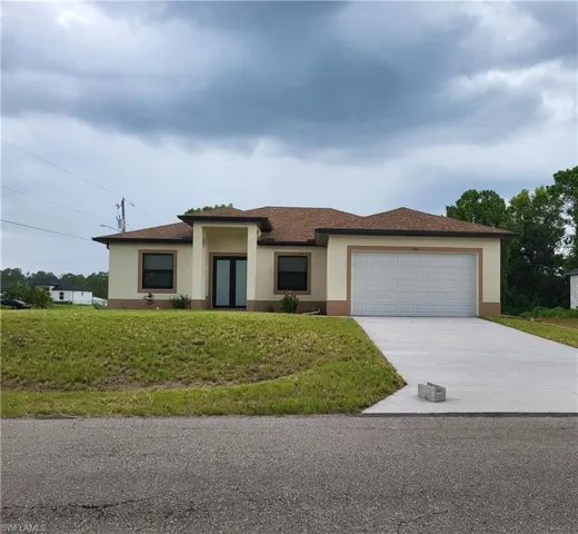 Prairie-style home featuring stucco siding, a garage, driveway, and a front yard