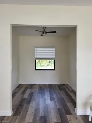 Empty room with dark wood finished floors and a ceiling fan