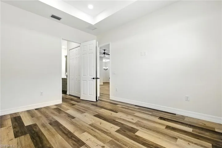 Unfurnished living room with light wood-style flooring, a tray ceiling, recessed lighting, french doors, and ceiling fan