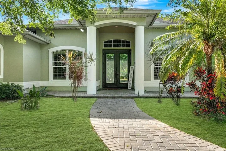 View of exterior entry with french doors and a lawn