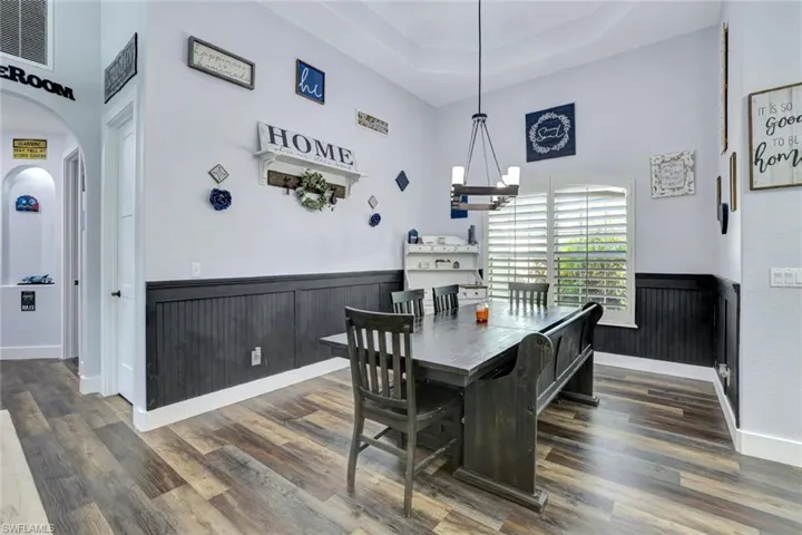 Dining area featuring a notable chandelier, a tray ceiling, a high ceiling, and dark hardwood / wood-style flooring