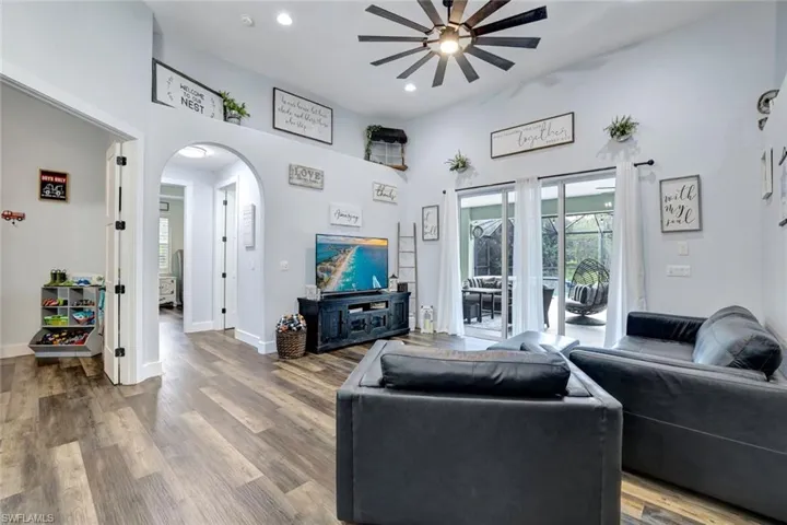 Living room featuring a high ceiling, hardwood / wood-style flooring, and ceiling fan