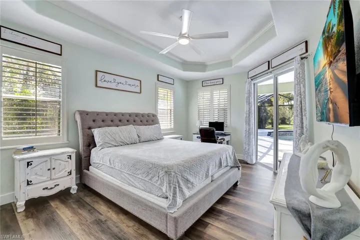 Bedroom with dark hardwood / wood-style floors, access to outside, a tray ceiling, crown molding, and ceiling fan
