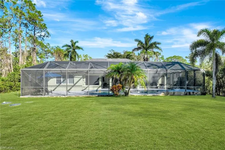 Back of property with a patio area, a lanai, and a yard