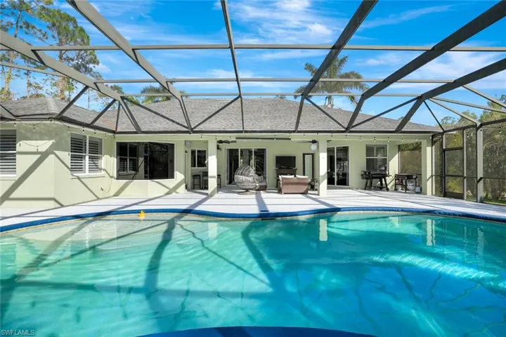 View of pool with a patio, glass enclosure, and ceiling fan