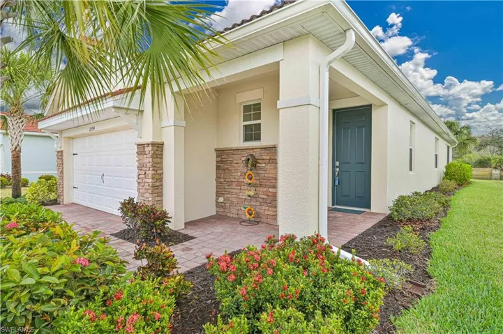 Entrance to property with stone siding, stucco siding, a garage, and a porch