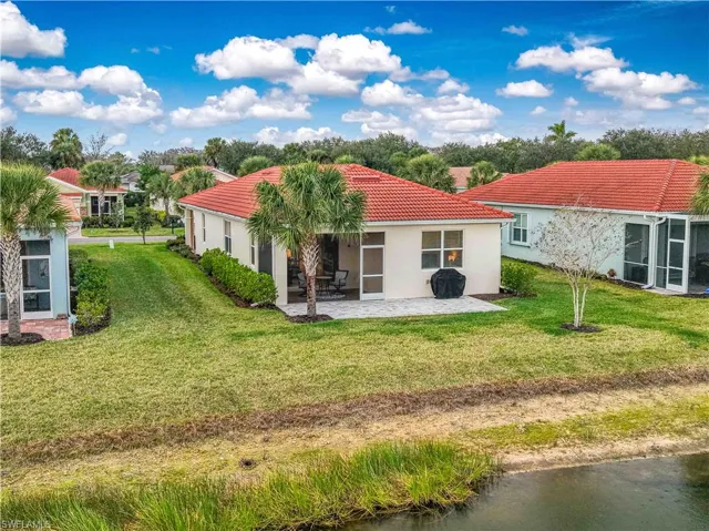 Back of property with stucco siding, a tile roof, a sunroom, and a lawn