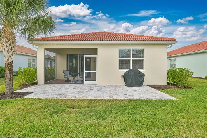 Rear view of property with a tiled roof, a yard, a sunroom, and a patio