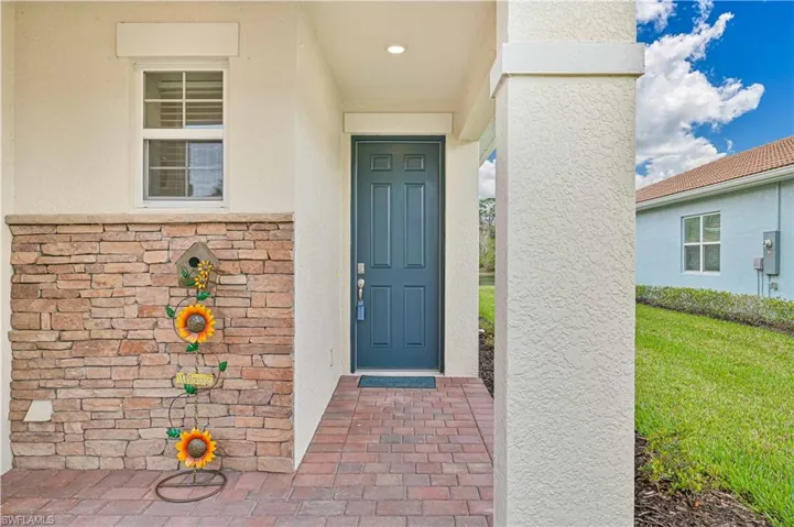 Property entrance featuring stucco siding, stone siding, and a yard