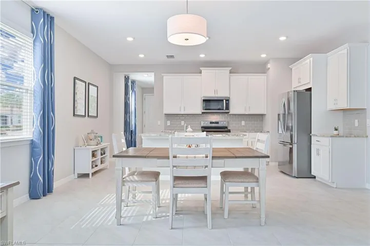 Kitchen with stainless steel appliances, white cabinets, backsplash, and recessed lighting