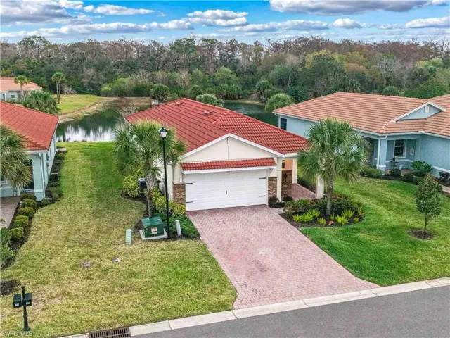 View of front of property featuring a tiled roof, a front yard, decorative driveway, a garage, and stone siding