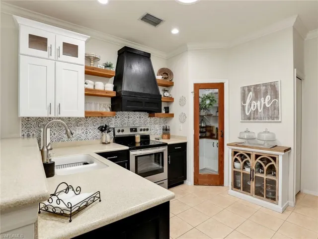 Kitchen with visible vents, a sink, open shelves, extractor fan, and electric range