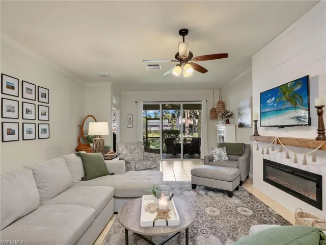 Living room with ceiling fan, ornamental molding, a fireplace, and visible vents