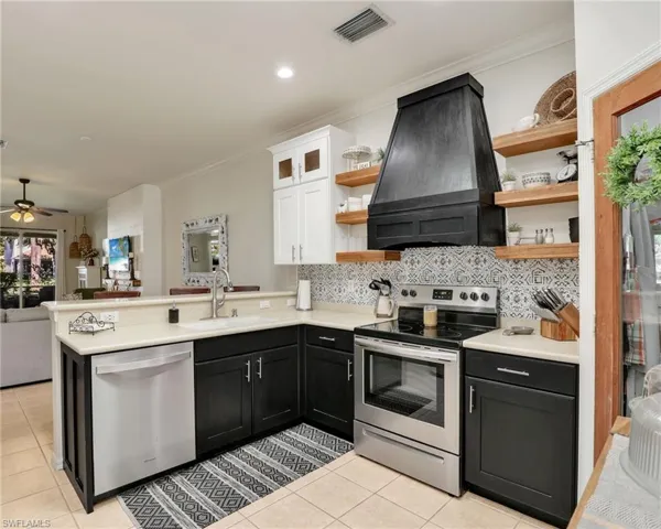 Kitchen with extractor fan, a sink, appliances with stainless steel finishes, and open shelves