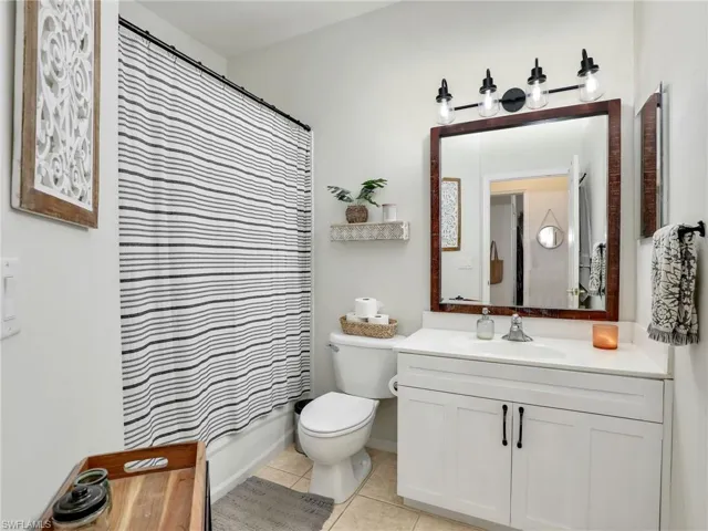 Bathroom featuring tile patterned flooring, vanity, toilet, and shower / tub combo with curtain
