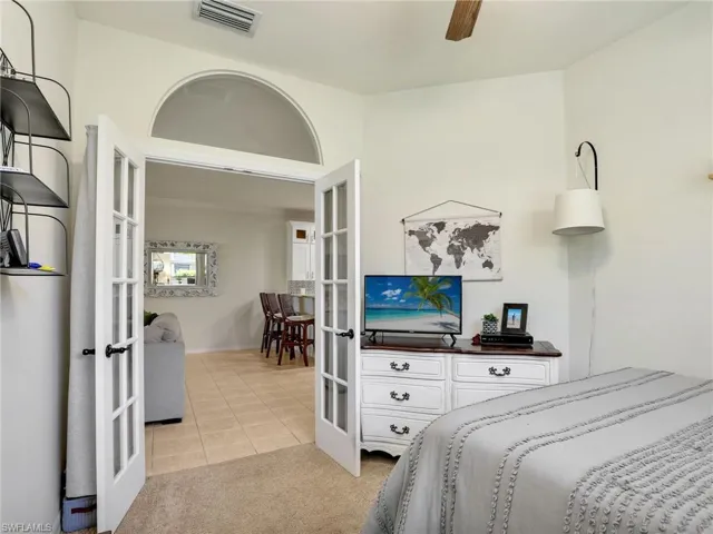Bedroom featuring light carpet, visible vents, french doors, and light tile patterned floors