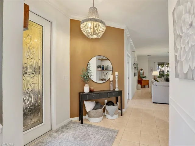 Corridor featuring light tile patterned flooring, ornamental molding, baseboards, and a chandelier