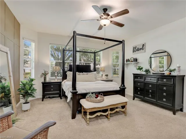 Bedroom featuring light colored carpet, multiple windows, and ceiling fan