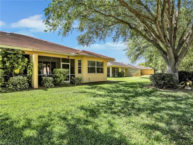 Back of house featuring stucco siding, a tiled roof, and a yard