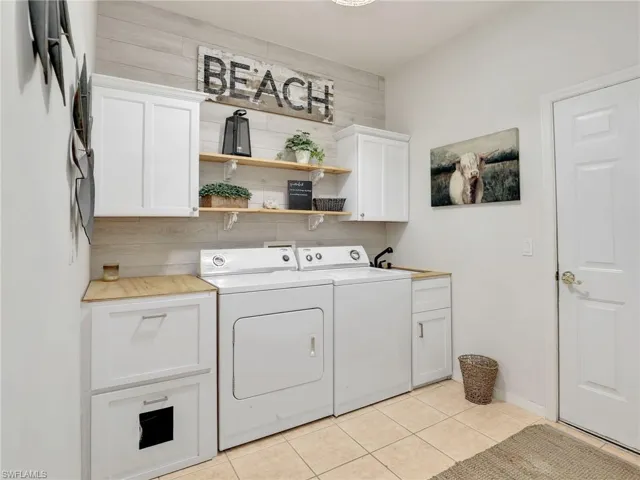 Washroom with independent washer and dryer, cabinet space, a sink, and light tile patterned floors