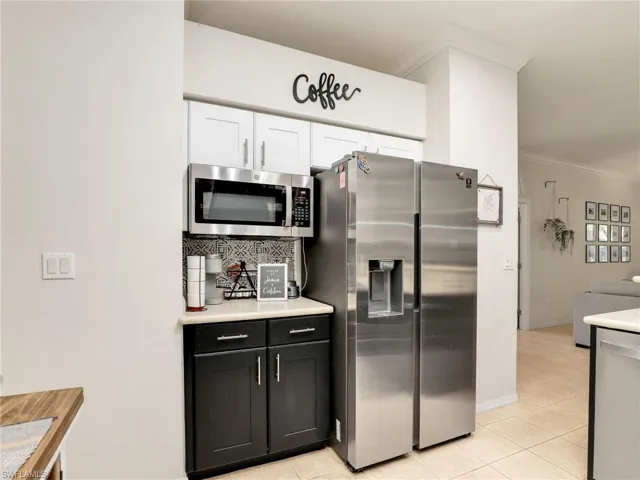 Kitchen with light tile patterned flooring, stainless steel appliances, crown molding, and tasteful backsplash