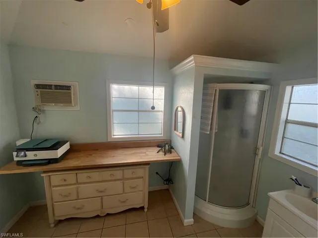 Bathroom with vanity, a shower stall, ceiling fan, and light tile patterned floors