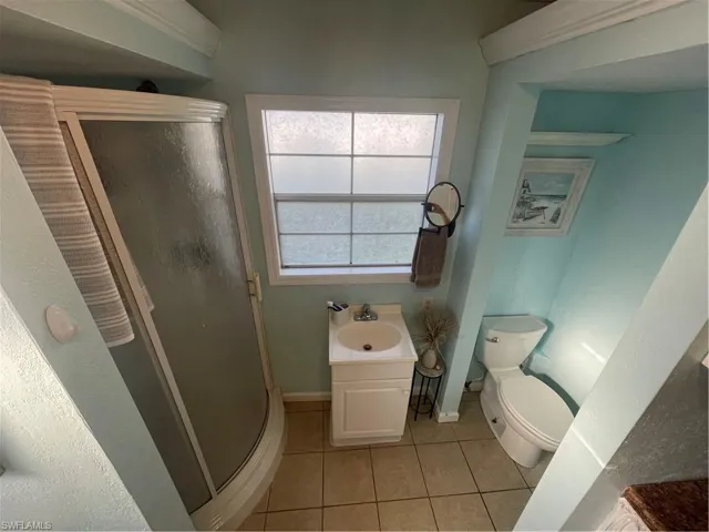 Full bathroom featuring a shower stall, light tile patterned flooring, and vanity