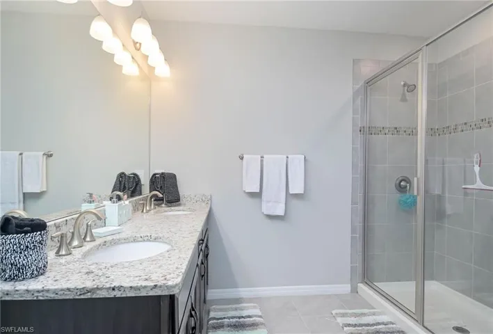 Bathroom featuring vanity, a shower with shower door, and tile patterned flooring