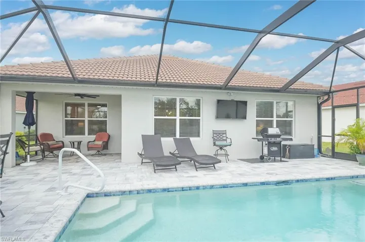 Rear view of house with glass enclosure, ceiling fan, and a patio area