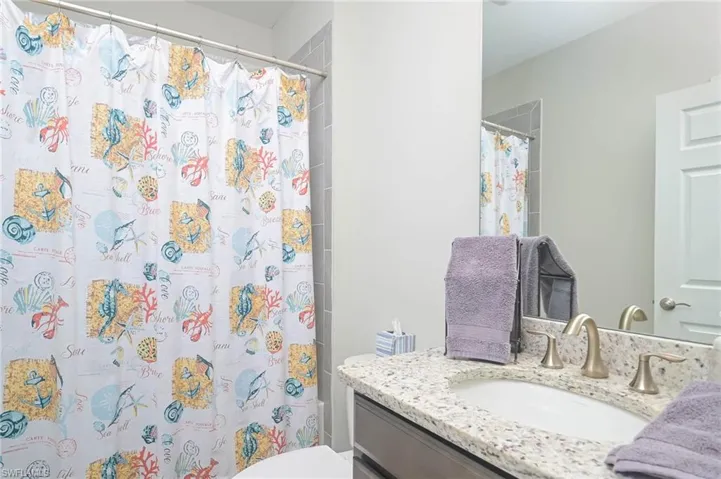 Bathroom featuring toilet, vanity, and curtained shower