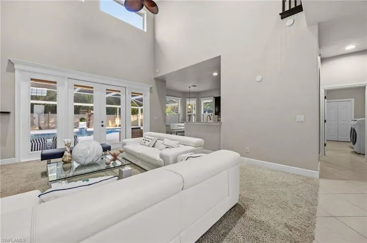 Living area featuring light tile patterned floors, french doors, a high ceiling, and light colored carpet