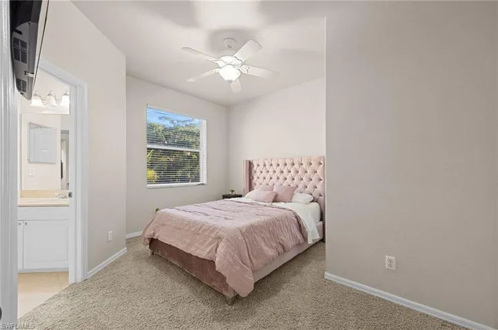 Bedroom featuring light carpet, a ceiling fan, and ensuite bath