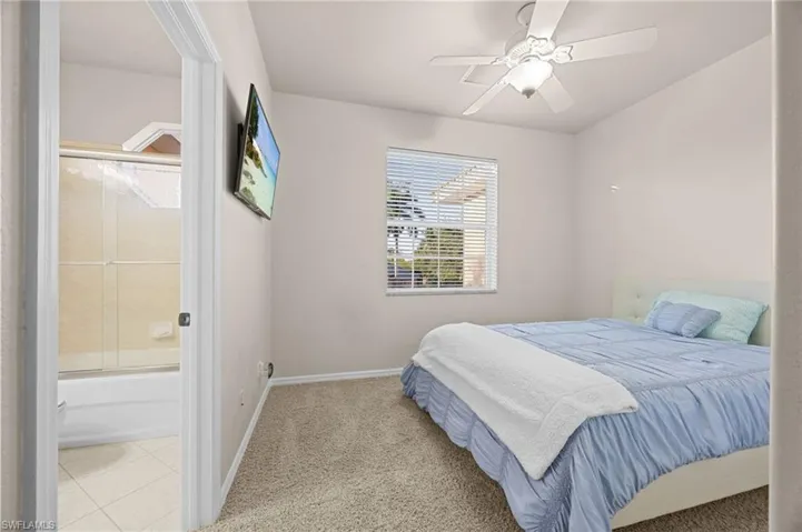 Carpeted bedroom featuring a ceiling fan and tile patterned floors