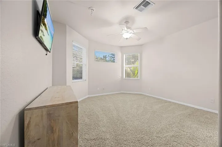 Carpeted empty room with baseboards and a ceiling fan
