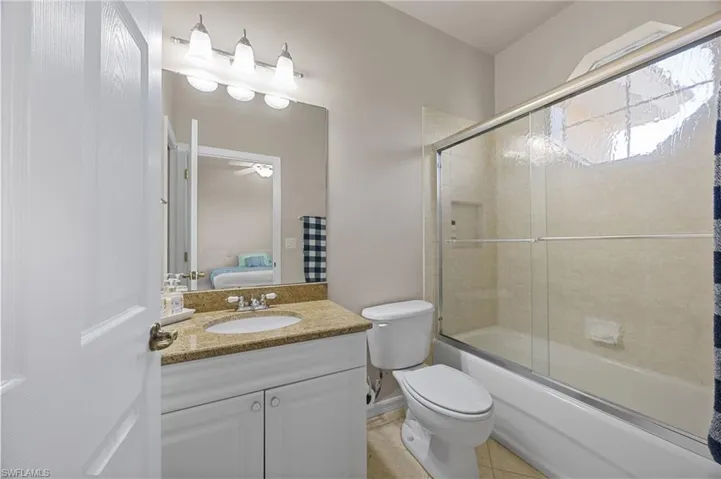 Bathroom featuring bath / shower combo with glass door, vanity, light tile patterned floors, and ensuite bath