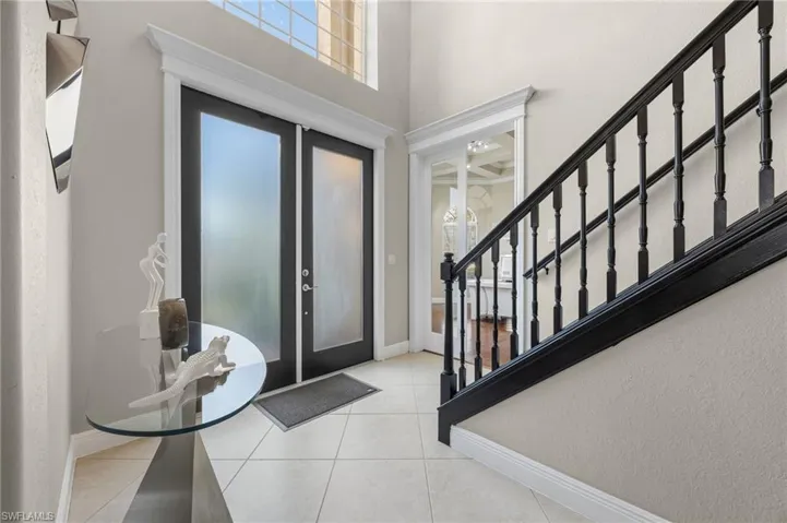 Entrance foyer featuring french doors, healthy amount of natural light, a towering ceiling, and tile patterned floors