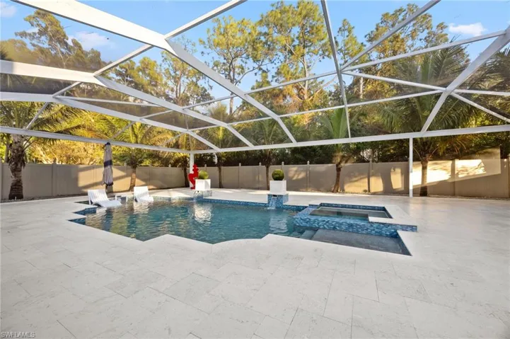 View of pool with a lanai, a pool with connected hot tub, a fenced backyard, and a sunroom