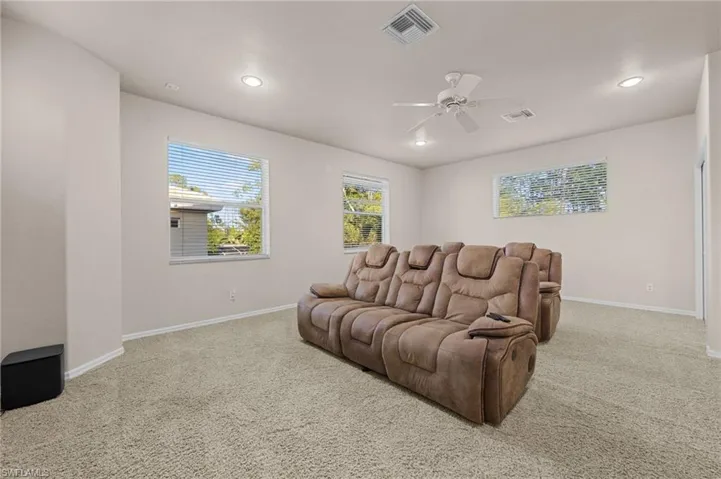 Cinema room with light carpet, ceiling fan, and recessed lighting