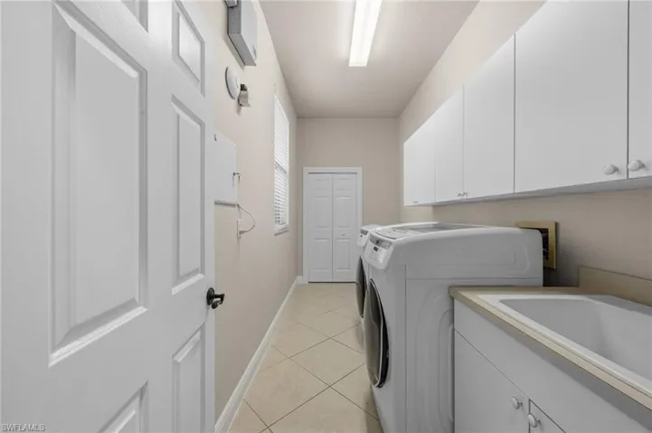 Laundry area with light tile patterned flooring, cabinet space, and washing machine and clothes dryer