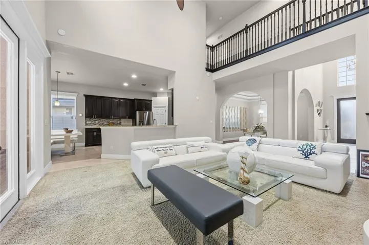 Living room featuring light carpet, arched walkways, recessed lighting, and a high ceiling