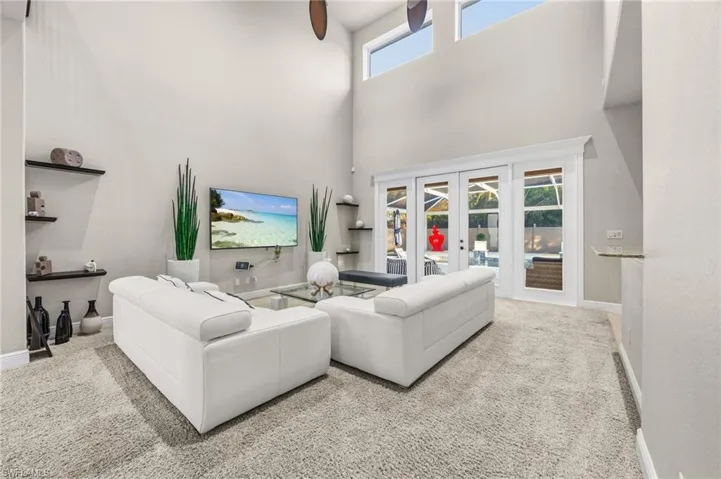 Carpeted living area with french doors and a towering ceiling