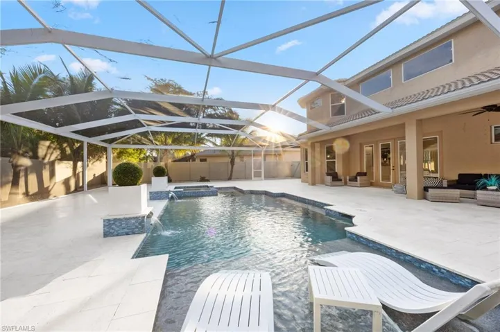 View of pool with a jacuzzi, a sunroom, a patio, an outdoor hangout area, and glass enclosure
